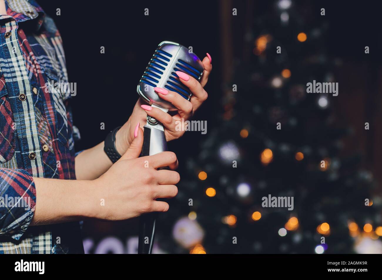 Weibliche Hand, die ein einziges Retro-Mikrofon vor bunten Hintergrund Stockfoto