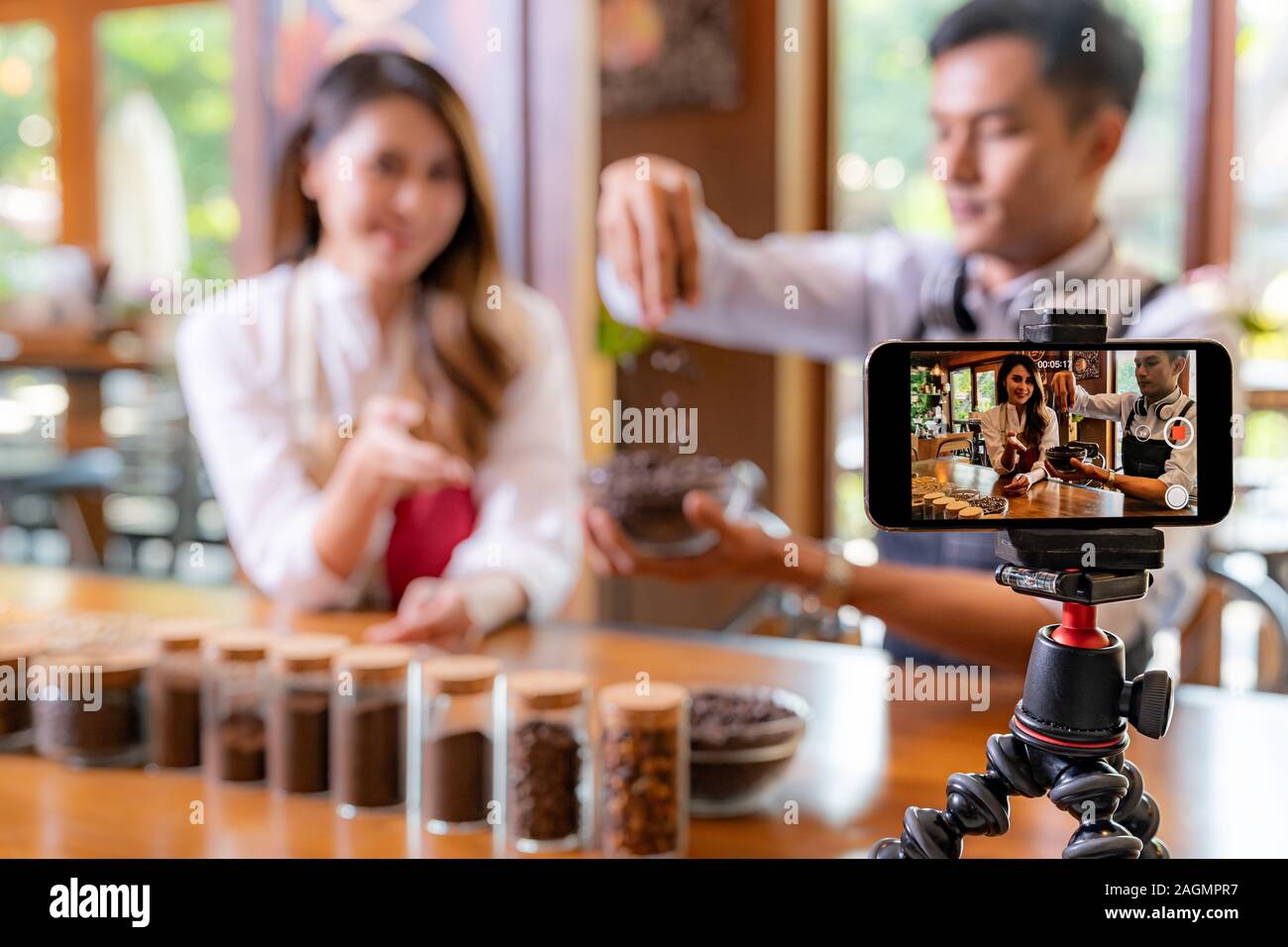 VLOG von jungen erwachsenen Asiatischen Eigentümer Unternehmer bewerten cafe Coffee Shop und Leben in sozialen Medien für Online Marketing mit Smart Phone im Cafe. Mit fo Stockfoto