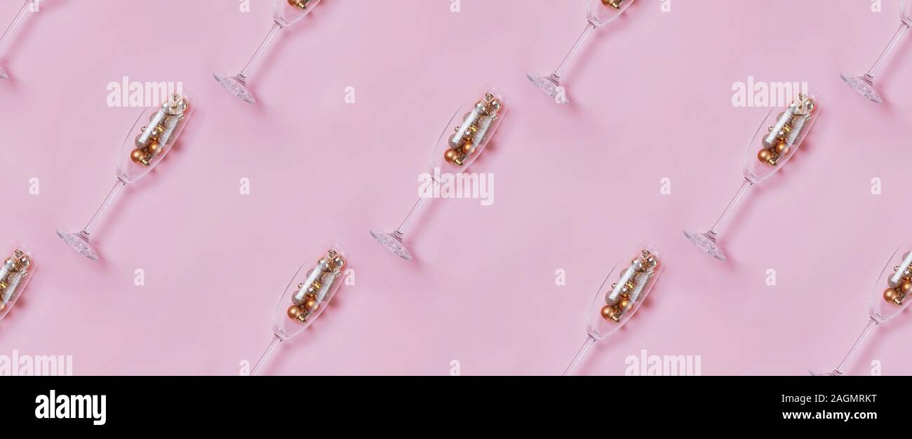 Champagner Gläser mit goldenen und roten Kugeln im Inneren auf Pastell rosa Hintergrund Stockfoto