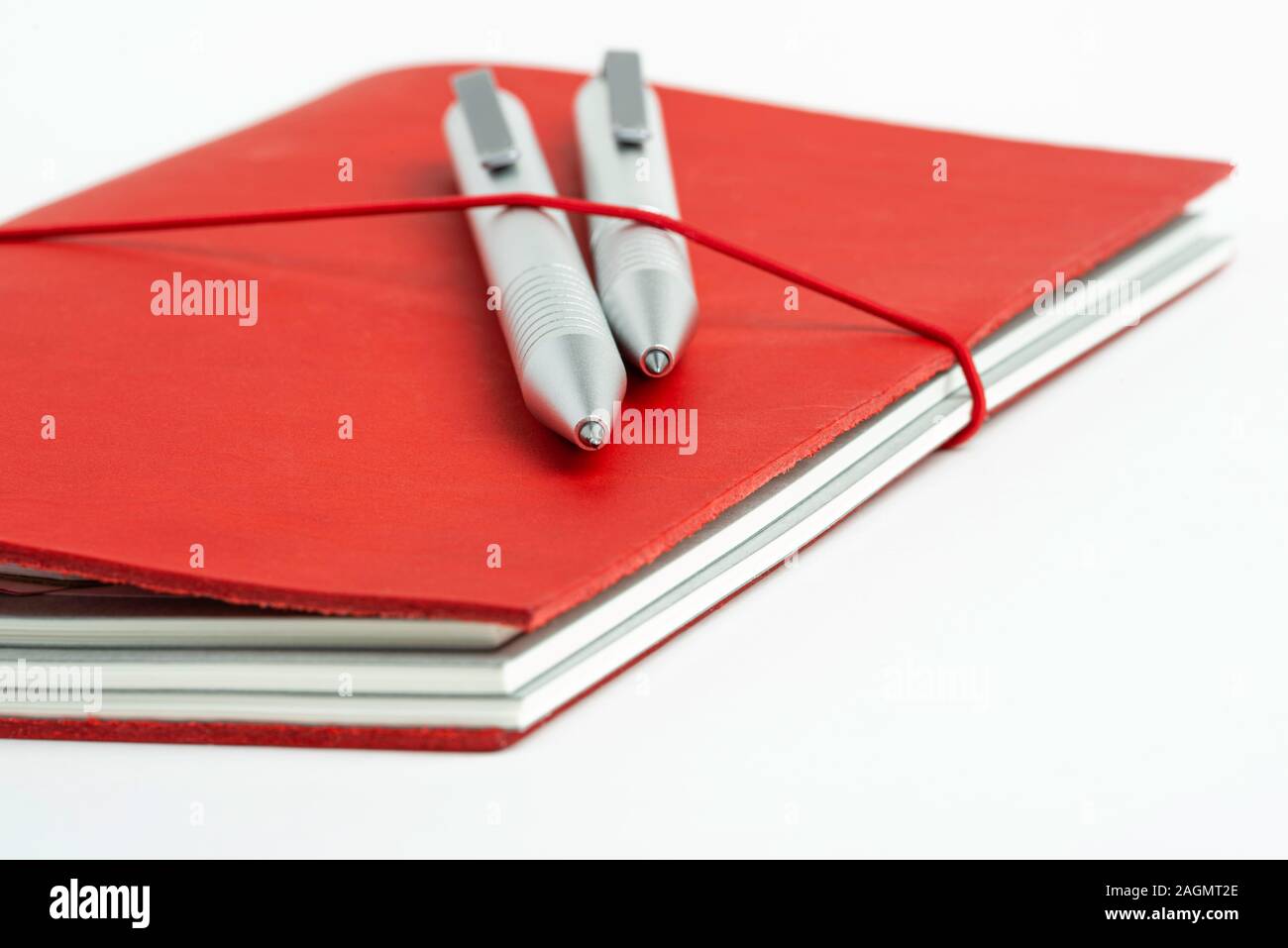 Ein Journal mit rotem Leder und elastischem Band sichern zwei metallic Kugelschreiber. Stockfoto