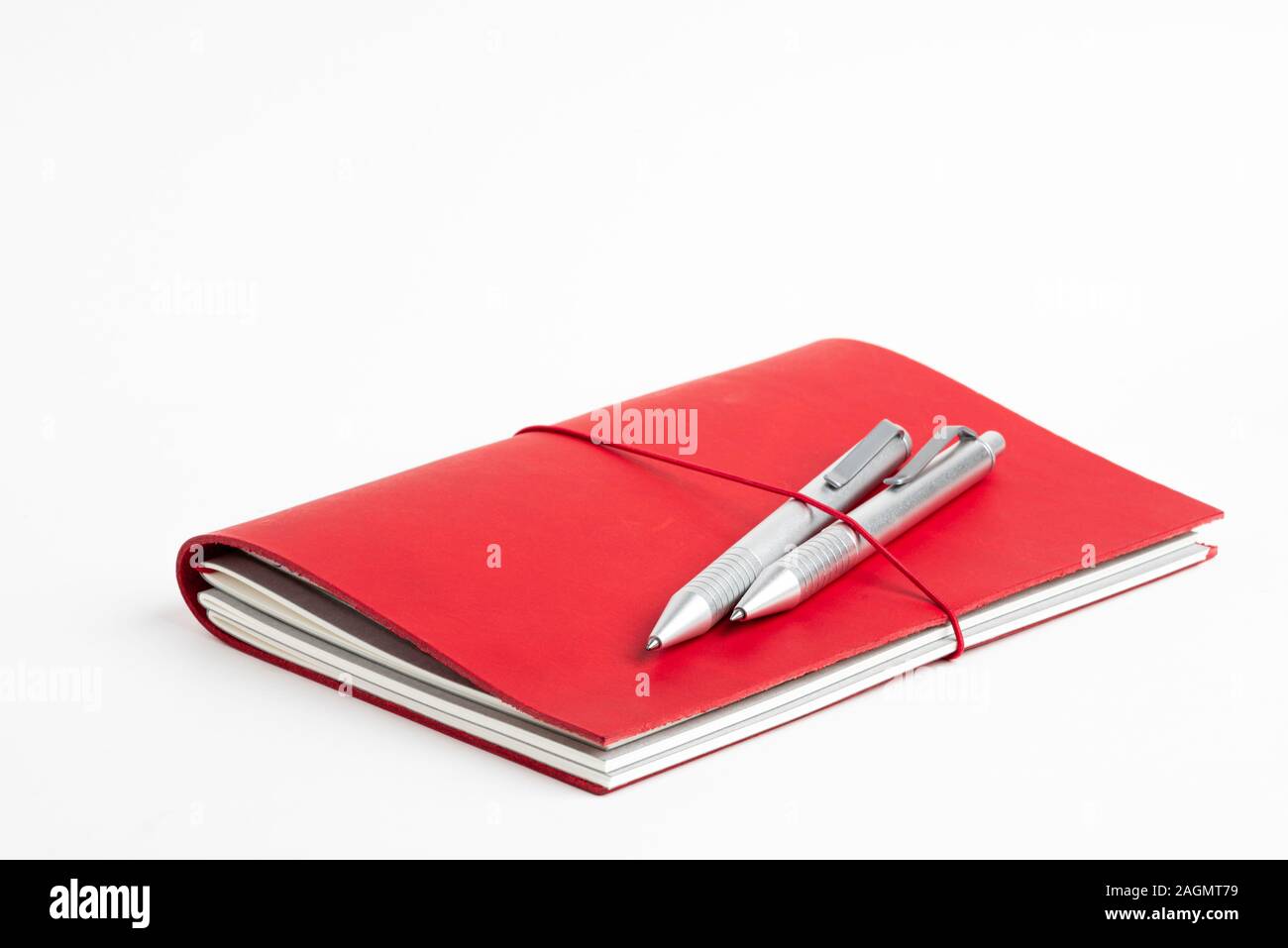 Ein Journal mit rotem Leder und elastischem Band sichern zwei metallic Kugelschreiber. Stockfoto