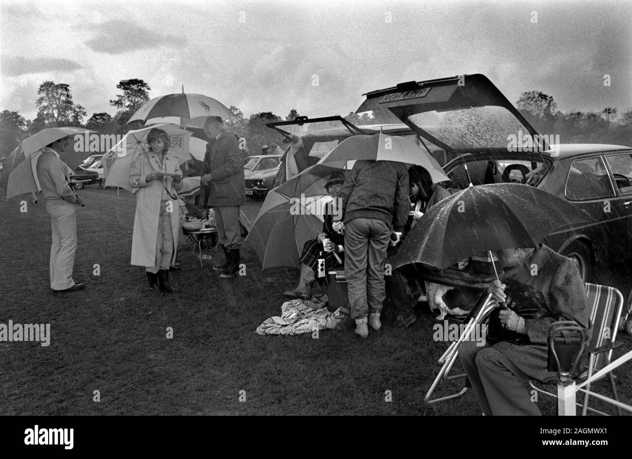 Schlechtes Wetter Großbritannien 1980s Menschen im Feiglinge Park Polo Club 1981 werden während der Mittagspause nass Picknicken im Freien Großbritannien HOMER SYKES Stockfoto