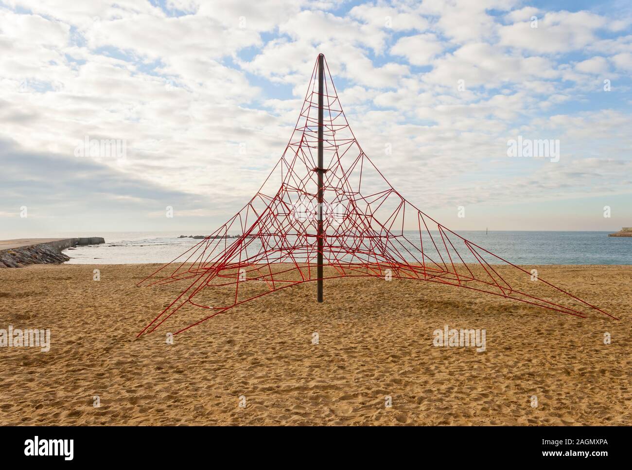 Leeres rotes Seil Pyramide Spielplatz zum Klettern. Niemand in der Strand und der Himmel ist bewölkt. Stockfoto