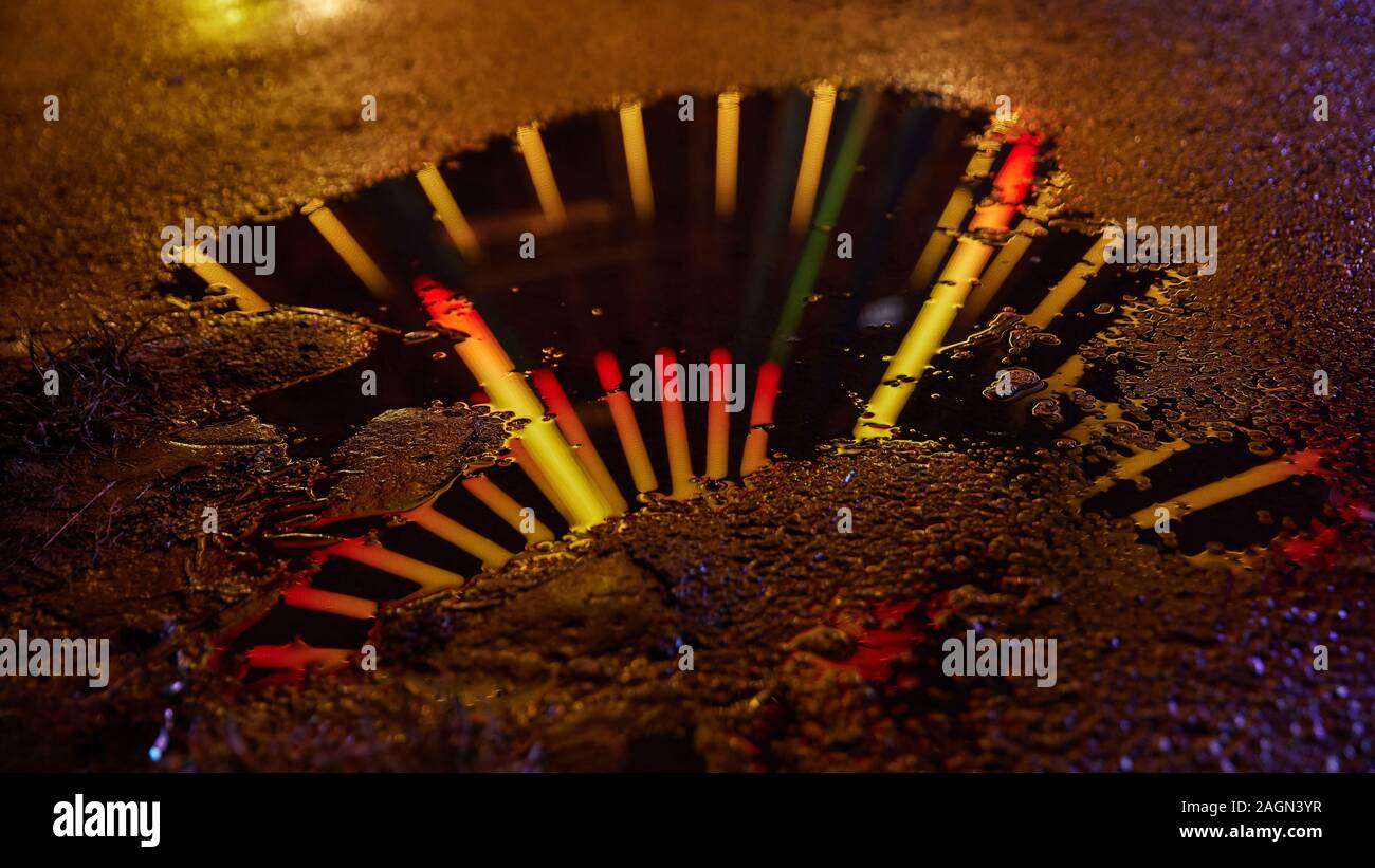 Beleuchtetes Riesenrad ist in der Nacht in einer Wasserlache auf der Kirmes oder ein Festival Stockfoto