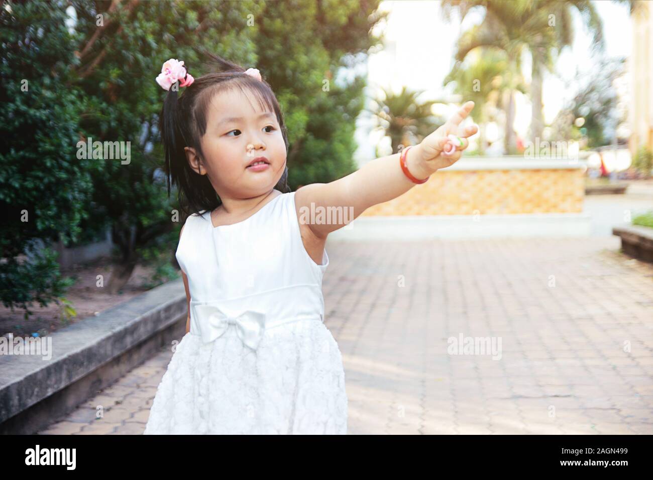 Kleine asiatische Mädchen stehen und poiting Finger nach rechts. Zukunft Kinder Konzept. Stockfoto