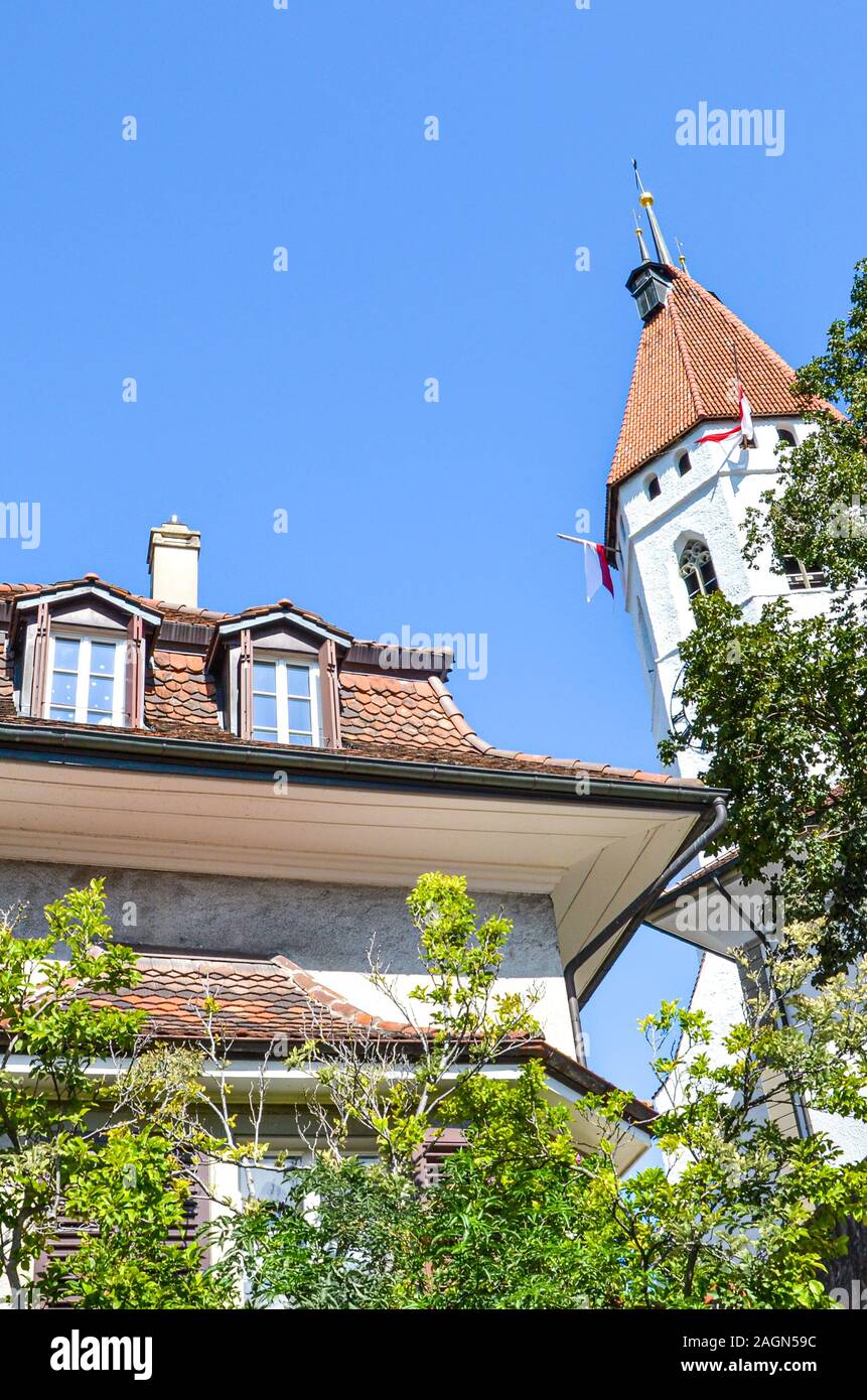 Die Stadtkirche Thun und Gebäude im historischen Zentrum von Thun, Schweiz. Die Reformierte Kirche hat einen schönen mittelalterlichen Turm und einem barocken Gang. Schweizer touristische Sehenswürdigkeit. Vertikale Foto. Stockfoto