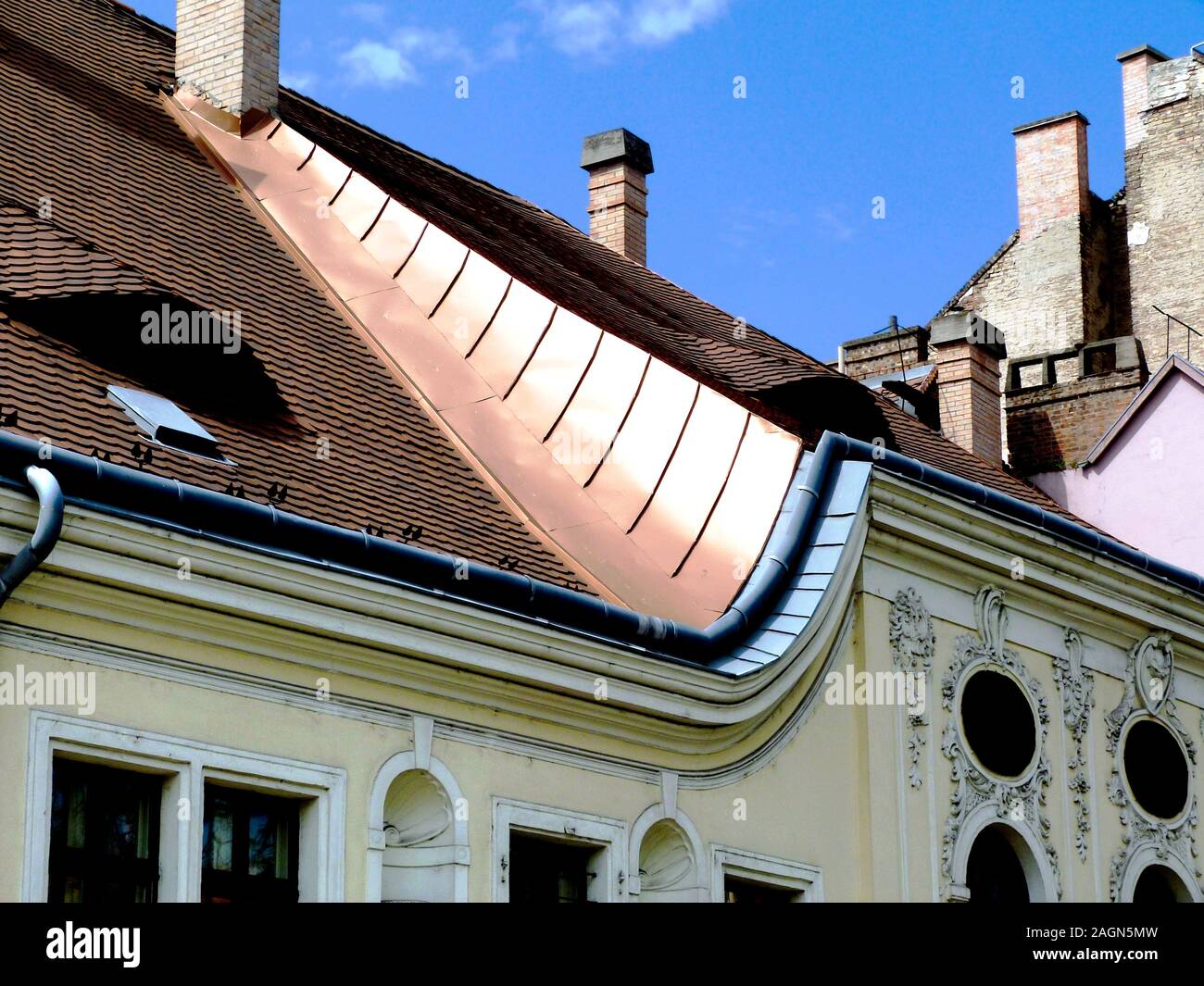 Kupferfarbene Blitzelemente und Tonfliesen, Schlafsäle, ovale Fenster, Stuckhöhe im Rokoko-Stil. Klassische Architektur. Ziegelschornsteine. Blauer Himmel Stockfoto