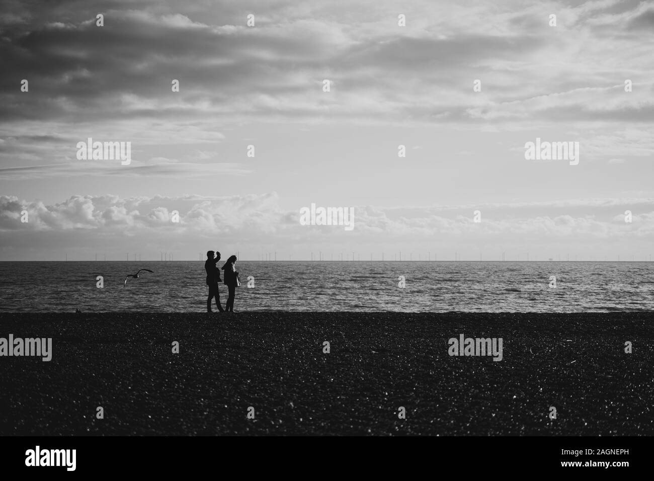 BRIGHTON, Großbritannien - 03.November 2019: Reste von Brighton Pier. Die Silhouetten, die laufen am Strand, Wellen erzeugen Wellen am Ufer, Ocean Spa Stockfoto