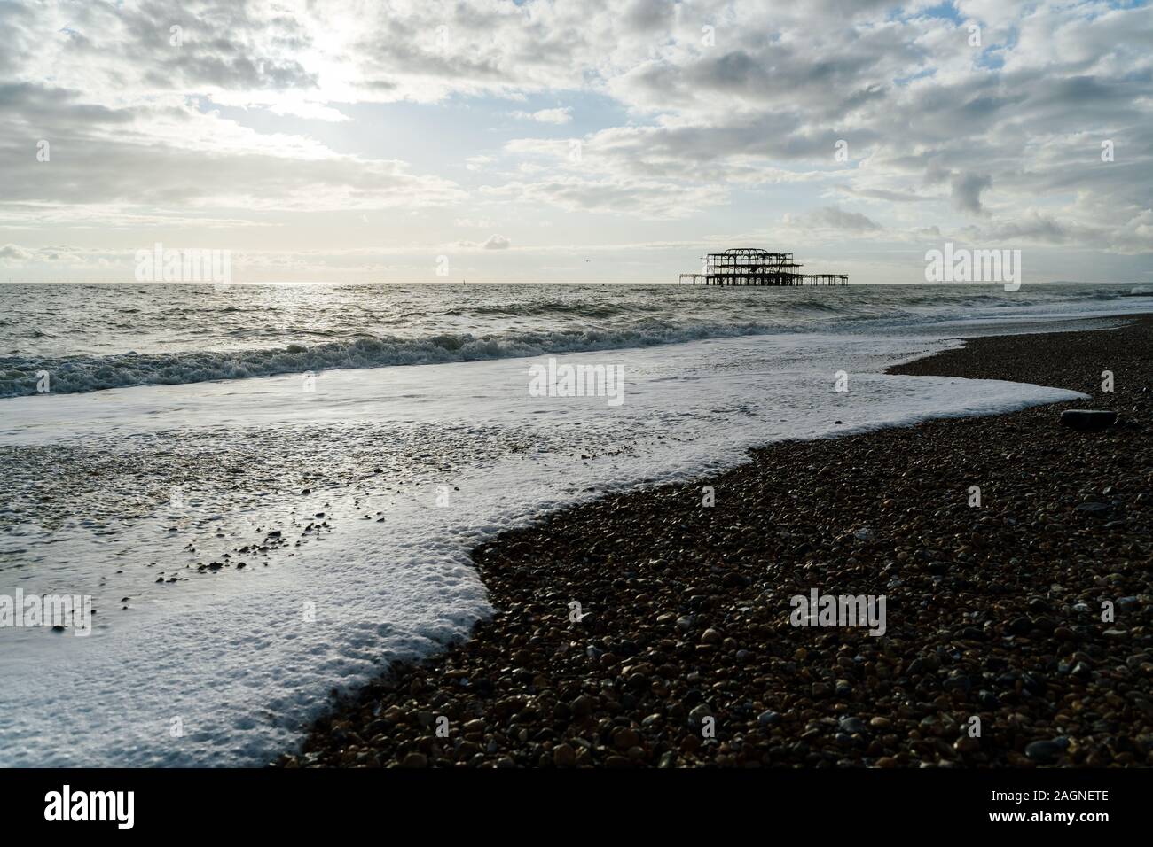 BRIGHTON, Großbritannien - 03.November 2019: Reste von Brighton Pier. Die Silhouetten, die laufen am Strand, Wellen erzeugen Wellen am Ufer, Ocean Spa Stockfoto