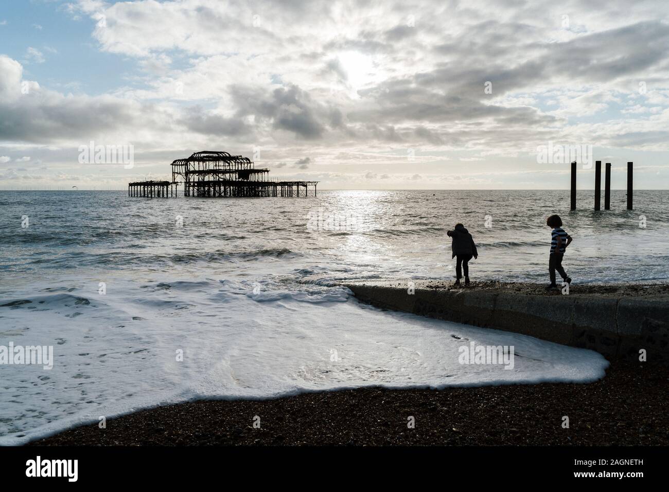 BRIGHTON, Großbritannien - 03.November 2019: Reste von Brighton Pier. Die Silhouetten, die laufen am Strand, Wellen erzeugen Wellen am Ufer, Ocean Spa Stockfoto