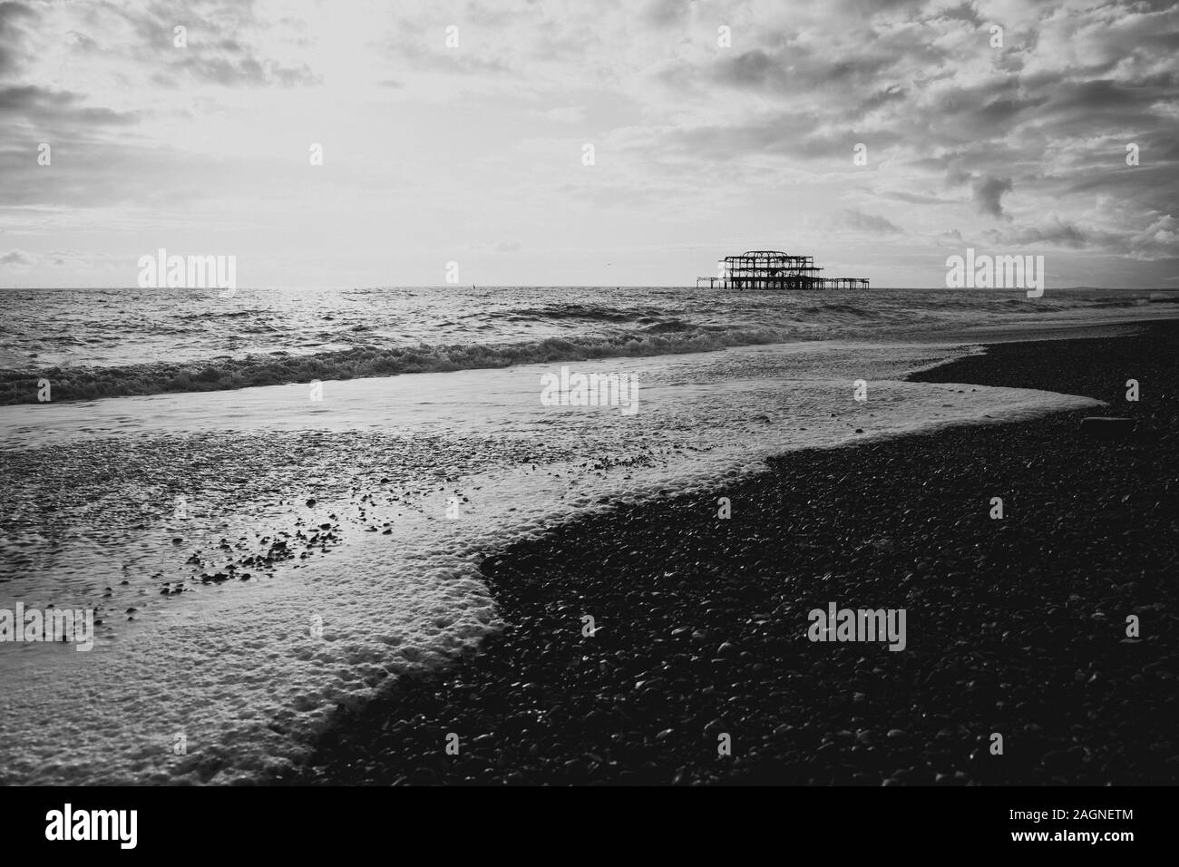 BRIGHTON, Großbritannien - 03.November 2019: Reste von Brighton Pier. Die Silhouetten, die laufen am Strand, Wellen erzeugen Wellen am Ufer, Ocean Spa Stockfoto