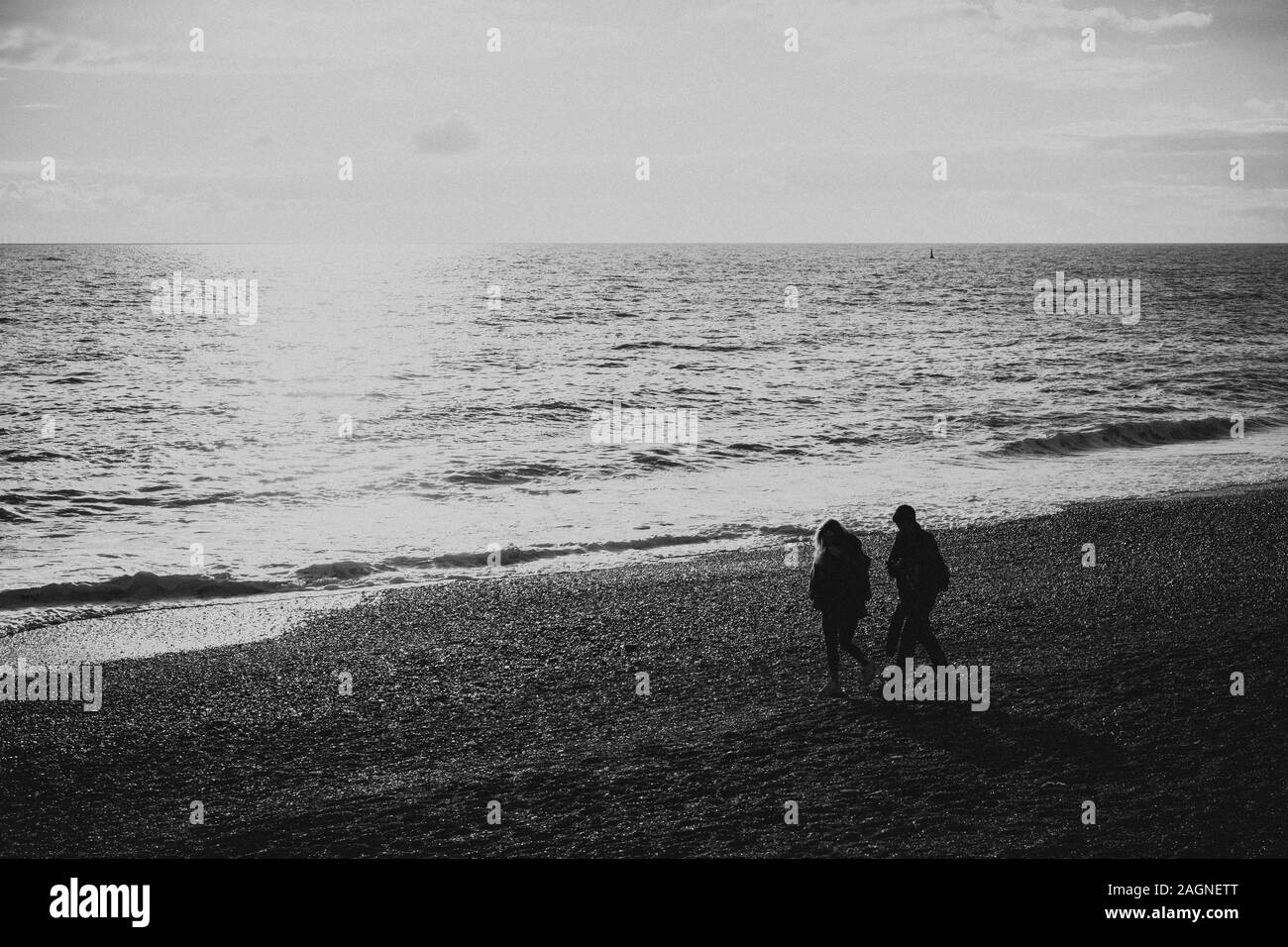 BRIGHTON, Großbritannien - 03.November 2019: Reste von Brighton Pier. Die Silhouetten, die laufen am Strand, Wellen erzeugen Wellen am Ufer, Ocean Spa Stockfoto