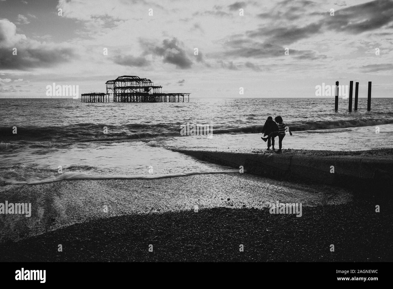 BRIGHTON, Großbritannien - 03.November 2019: Reste von Brighton Pier. Die Silhouetten, die laufen am Strand, Wellen erzeugen Wellen am Ufer, Ocean Spa Stockfoto
