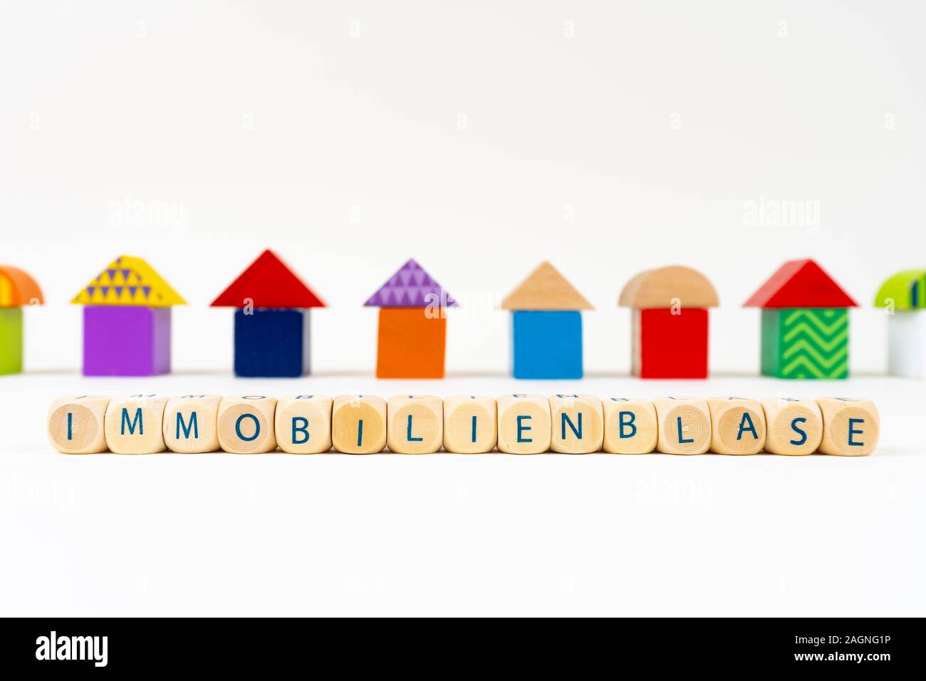 Holzblock mit Buchstaben sagen "immobilienblase" (Deutsch für Real Estate Bubble) vor bunten Spielzeug Häuser Stockfoto