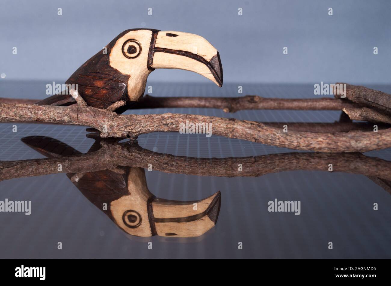 Schönen handgefertigten Holz- tucan Ornament auf e reflektierende Oberfläche zu einer farbenfrohen bachground. Stockfoto
