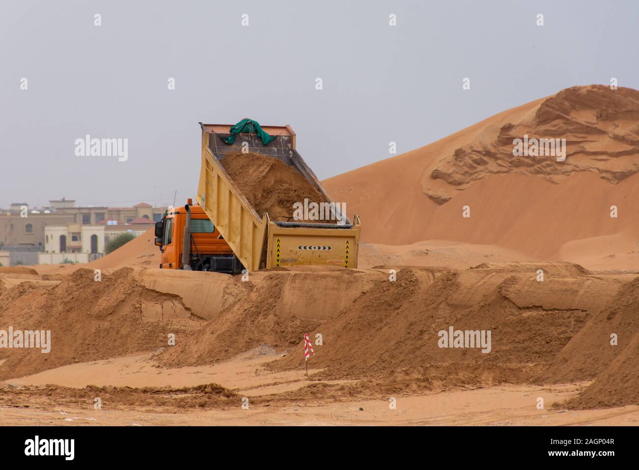 Dump Truck fahren durch Sand für den Bau der neuen Straße durch den Sand der Vorbereitung auf neue Entwicklung im Nahen und Mittleren Osten Stockfoto