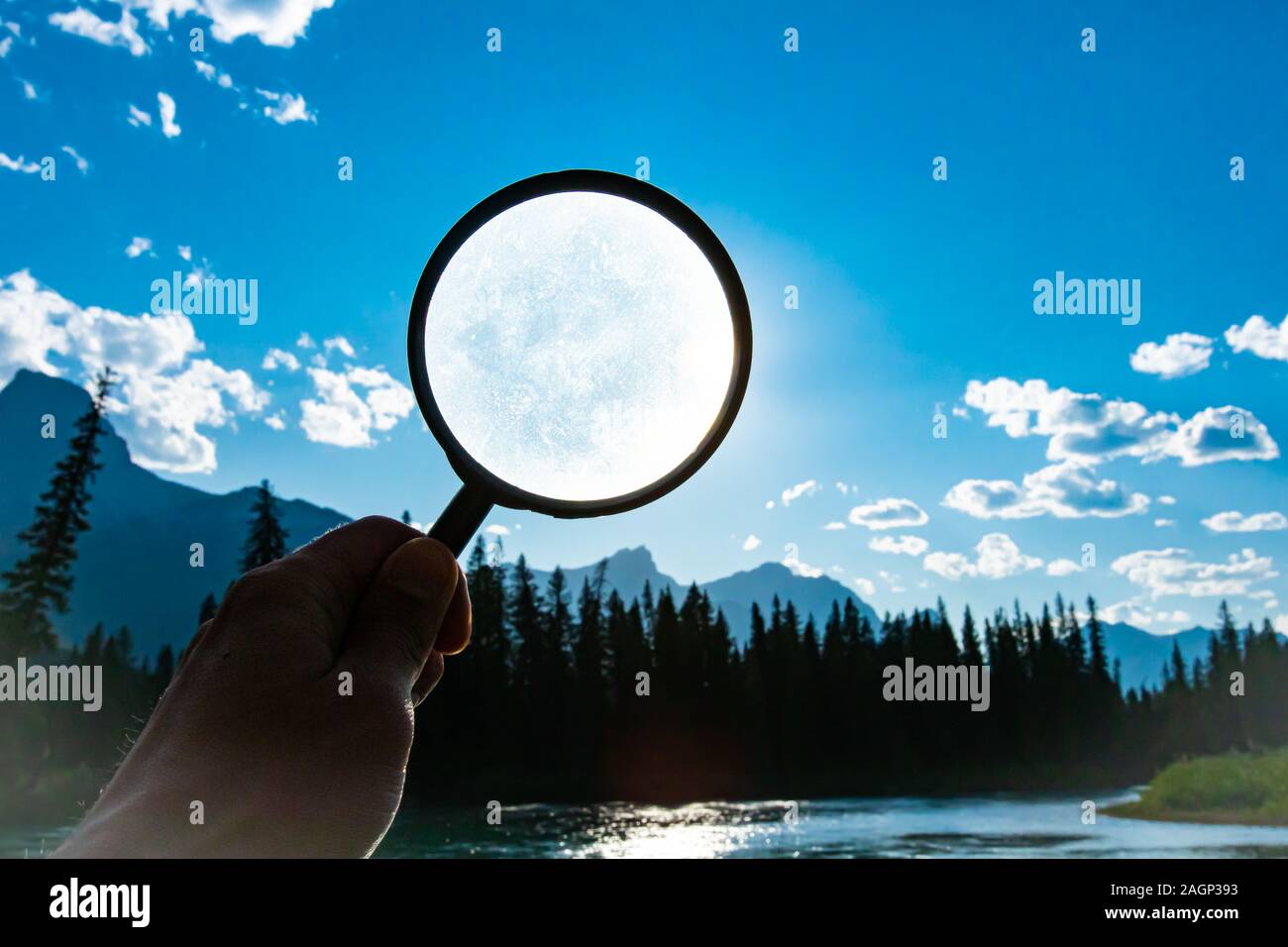 Mann mit einer Lupe über einen strahlend blauen Himmel mit vereinzelten Wolken im Sommer in der Natur mit Kopie Raum Stockfoto