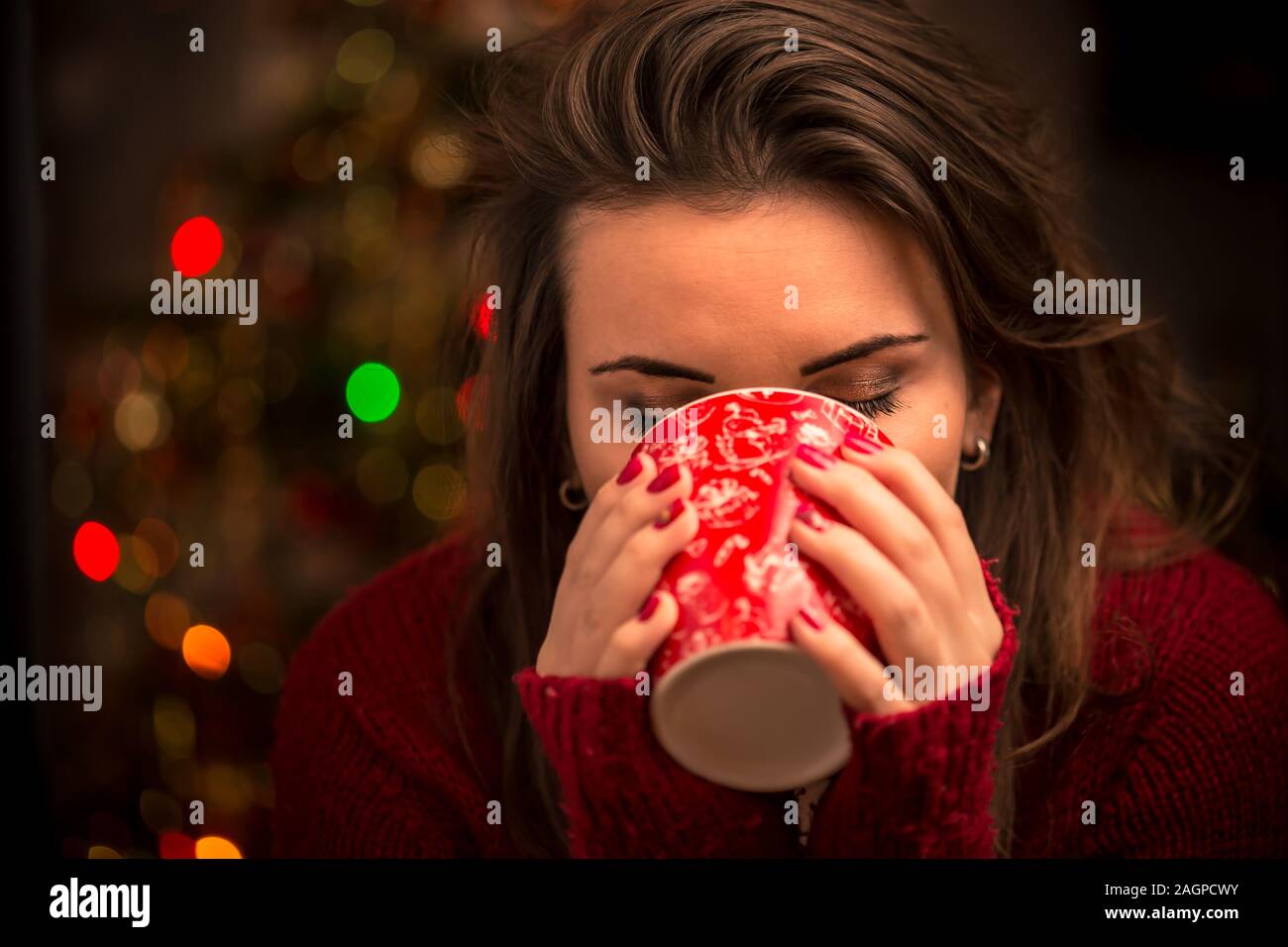 Abend, Freizeit, weihnachten, Winter und Menschen Konzept - glückliche junge Frau mit einer Tasse Kaffee oder Tee zu Hause. Gemütliches Konzept. Stockfoto