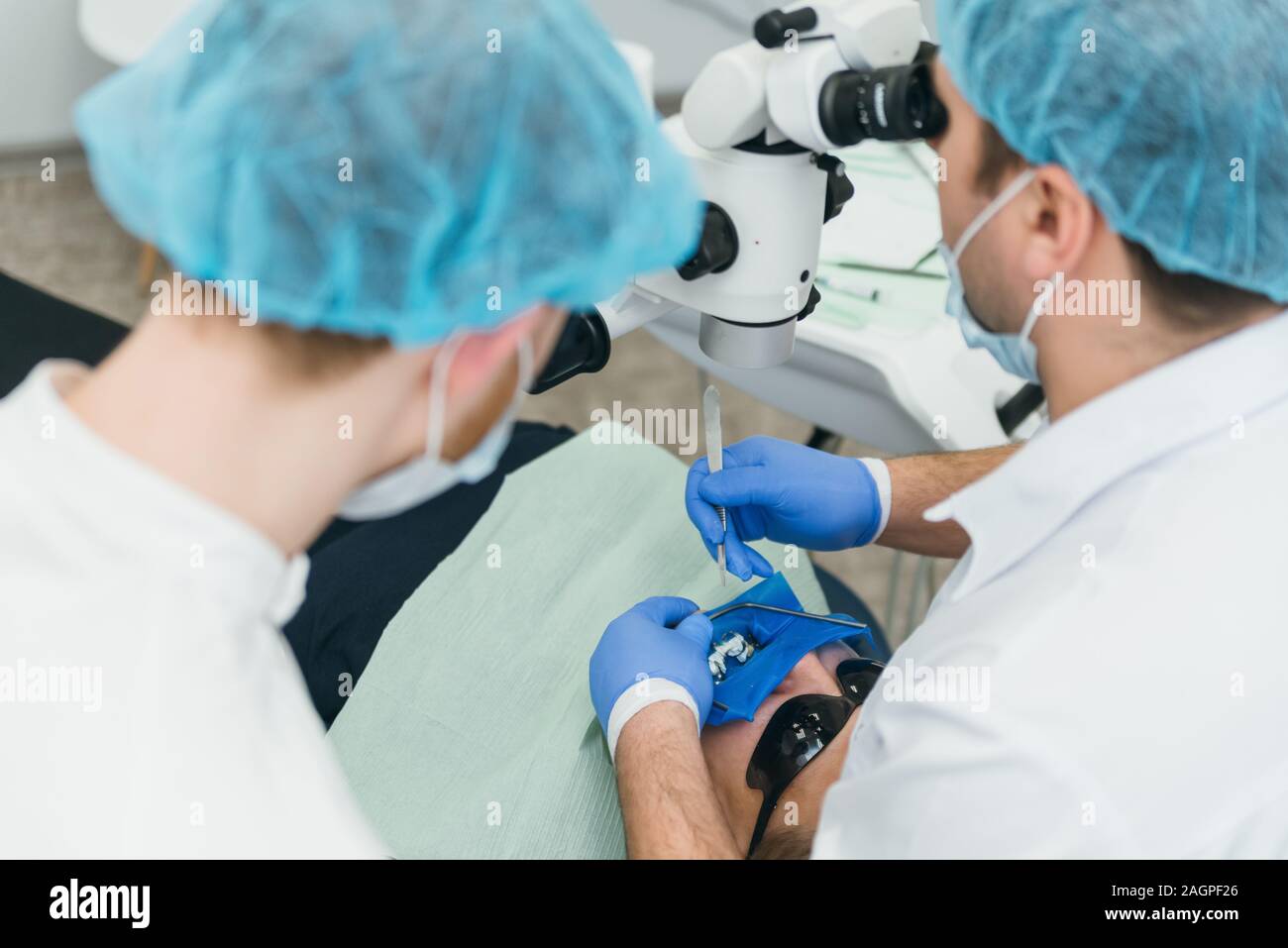 Arzt Mikroskop. Zahnarzt ist die Behandlung von Patienten in der modernen zahnmedizinischen Büro. Die Bedienung erfolgt mittels Fangdamms durchgeführt. Client wird eingefügt und wiederhergestellt Stockfoto