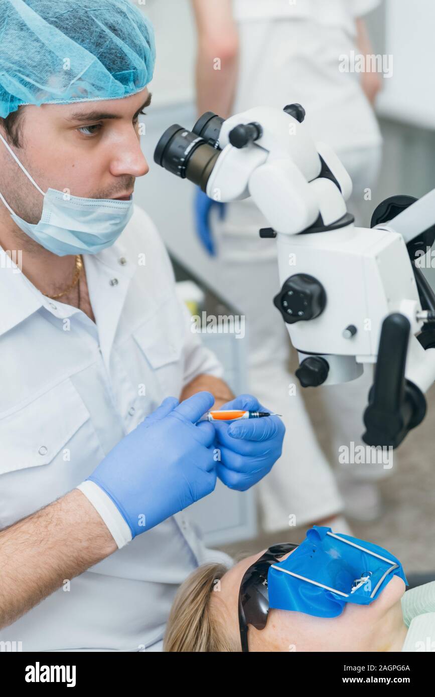 Arzt Mikroskop. Zahnarzt ist die Behandlung von Patienten in der modernen zahnmedizinischen Büro. Die Bedienung erfolgt mittels Fangdamms durchgeführt. Client wird eingefügt und wiederhergestellt Stockfoto