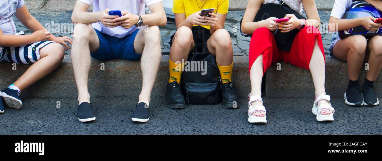 Gruppe Teenager sitzen mit Handys auf dem Bürgersteig, Ansicht von unten Stockfoto