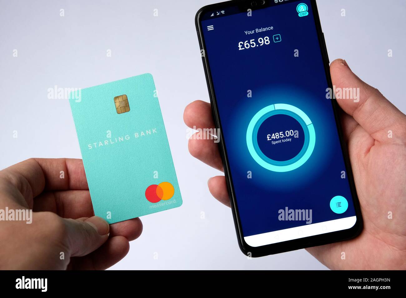 Starling Bankkarte und Starling App auf dem Smartphone in den Händen halten, auf weissem isoliert. Stockfoto
