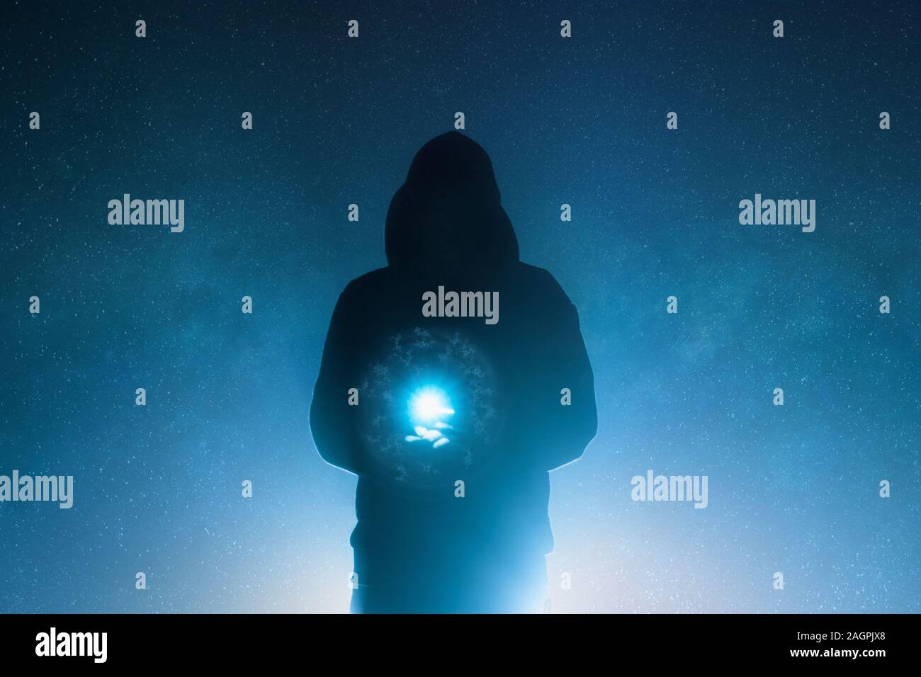 Eine geheimnisvolle Moody hooded Abbildung, die eine magische, sanftes Licht zurück gegen Licht und ein Universum von Sternen. Stockfoto