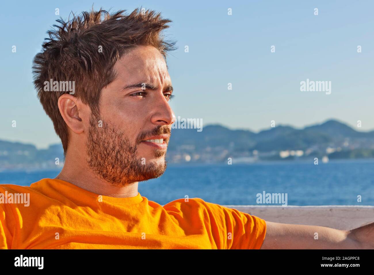 Ein junger zerzaust Rettungsschwimmer mit orange T-shirt am Strand rechts. Stockfoto