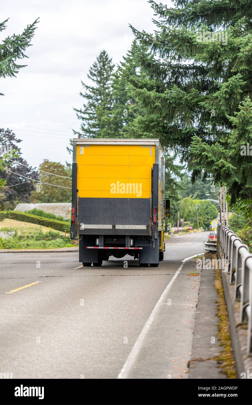 Big Rig gelb Tag cab Semi Truck für die lokalen Lieferungen Transport von kommerziellen Ladung in Box Anhänger mit Aufzug auf der Rückseite, auf die City Road wit Stockfoto