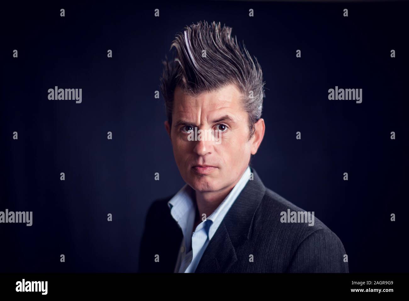 Handsone Mann mit Mohawk tragen Anzug vor schwarzem Hintergrund. Stockfoto