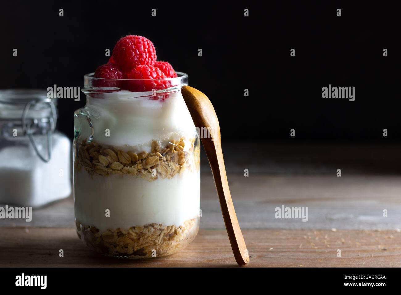 Gesund vegan Frühstück mit Joghurt mit Müsli und Himbeere auf einem dunklen Hintergrund mit Kopie Raum Stockfoto