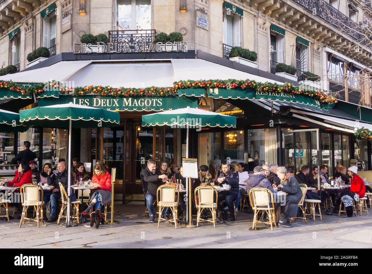 Paris Les Deux Magots - Gönner genießen Sie die Wintersonne im Les Deux Magots Cafe in der Saint-Germain-des-Prés von Paris, Frankreich, Europa. Stockfoto