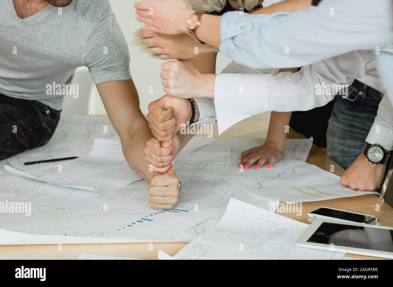 Corporate training Mitarbeiter bauen eine Pyramide von Fäusten auf den Tisch auf dem Tisch sind, federzeichnungen von Tabletten und Telefone Stockfoto