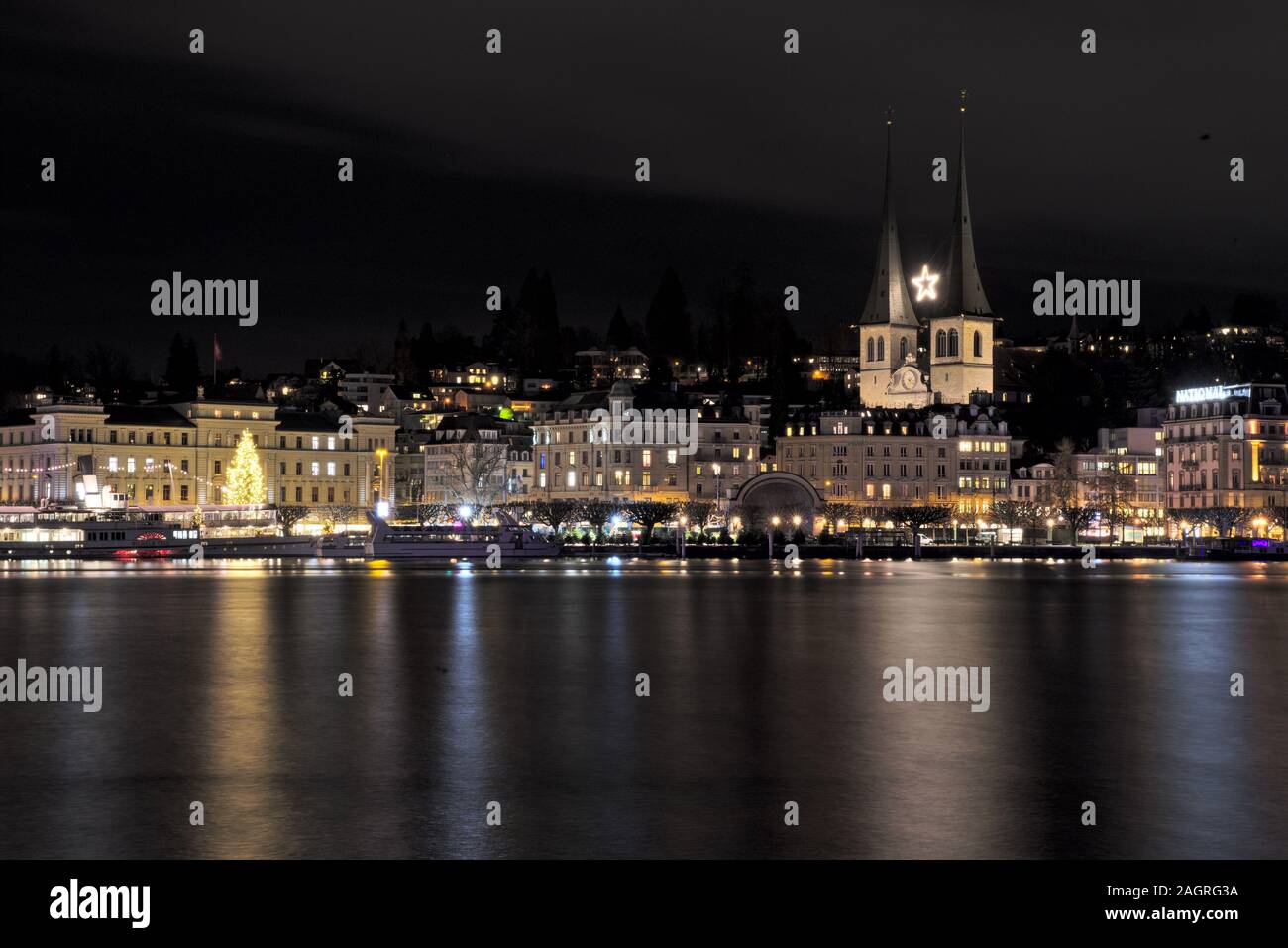 Weihnachtsbaum und Lichter vor der Hofkirche in Luzerner, Schweiz, reflektieren im Wasser erzeugen eine schöne weihnachtsstimmung. Stockfoto