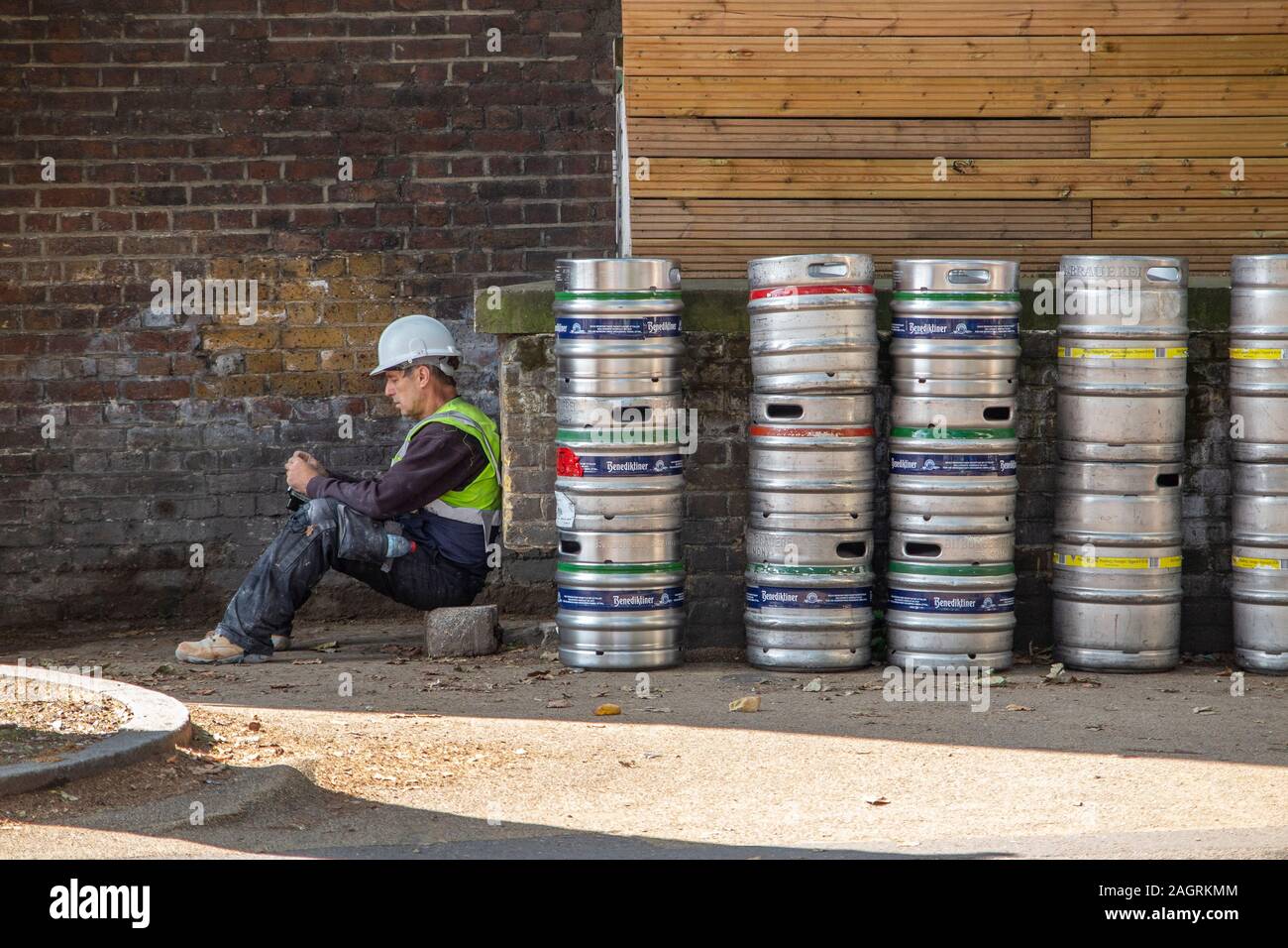 Ein Bauarbeiter entspannt auf eine Pause und sieht bei seinem Telefon Stockfoto