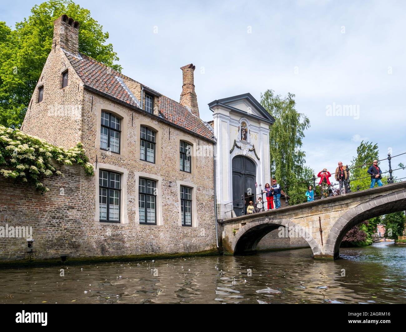 Menschen auf der Kanalbrücke und Eingangstor zum Begijnhof, Beginenhof in Brügge, Belgien. Stockfoto