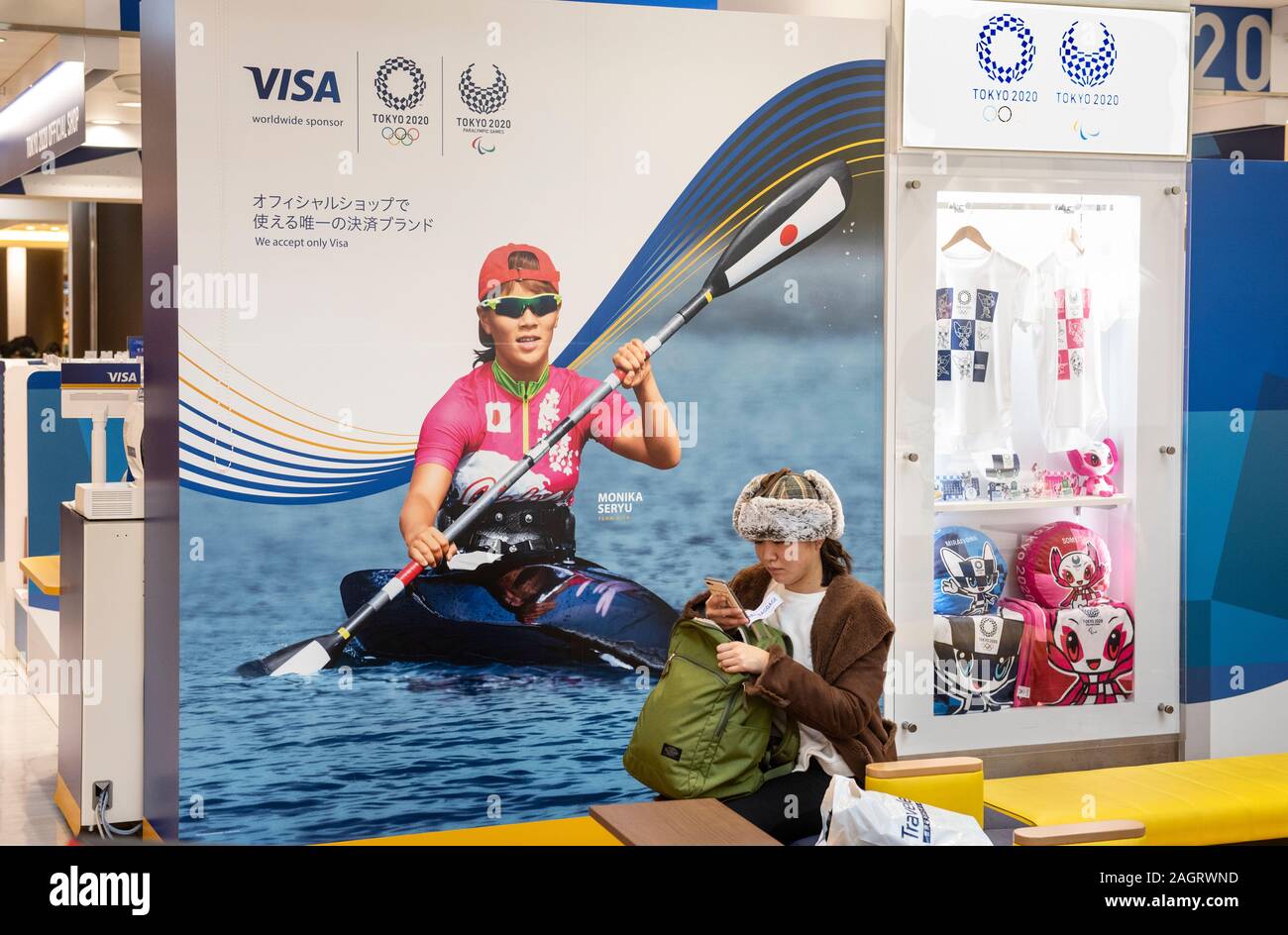 Eine Frau steht neben 2020 Tokio Olympischen Spielen und Paralympics offizielle store in Tokyo Narita Flughafen. Stockfoto