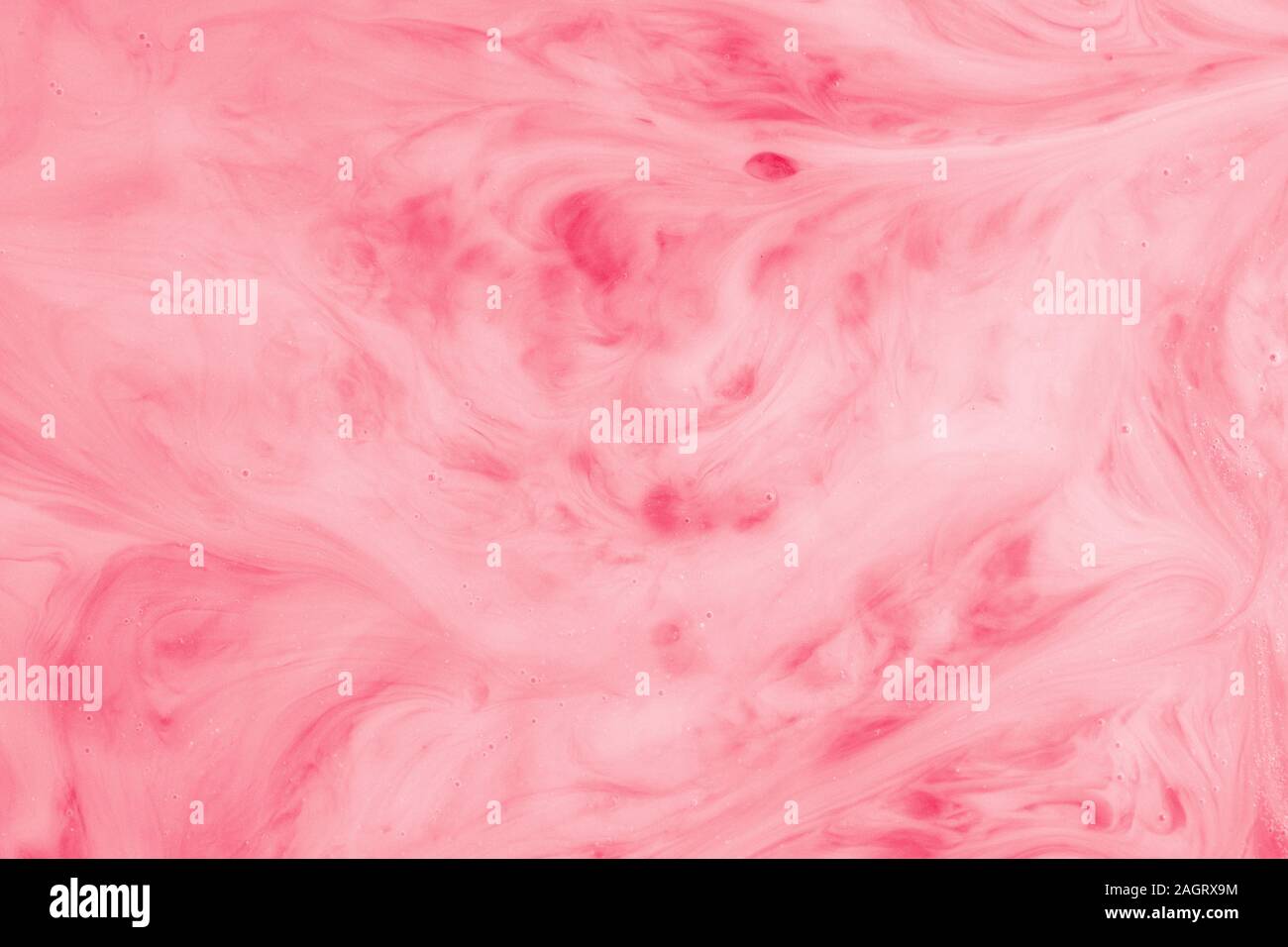 Ein Makro Foto von Tropfen rote Lebensmittelfarbe wirbelte und gemischt in dicken, cremigen weiße Milch Eine marmorierte Milchshake Effekt zu geben Stockfoto