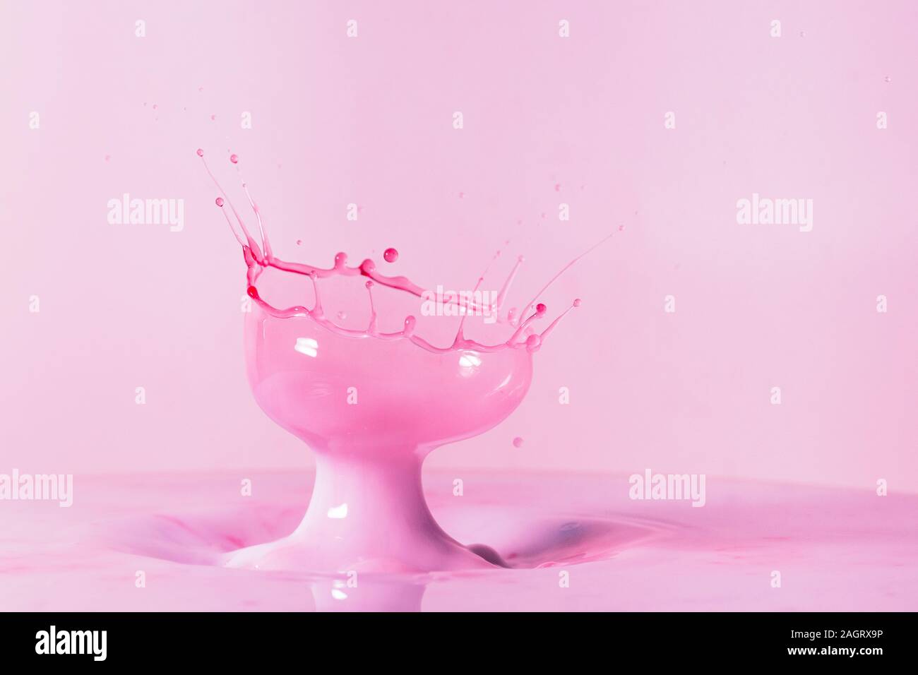 Ein Makro Foto von zwei Tropfen rote Lebensmittelfarbe Kollision in einem Pool von dicken, cremigen Milch mit Flash die Bewegung einzufrieren erfasst Stockfoto