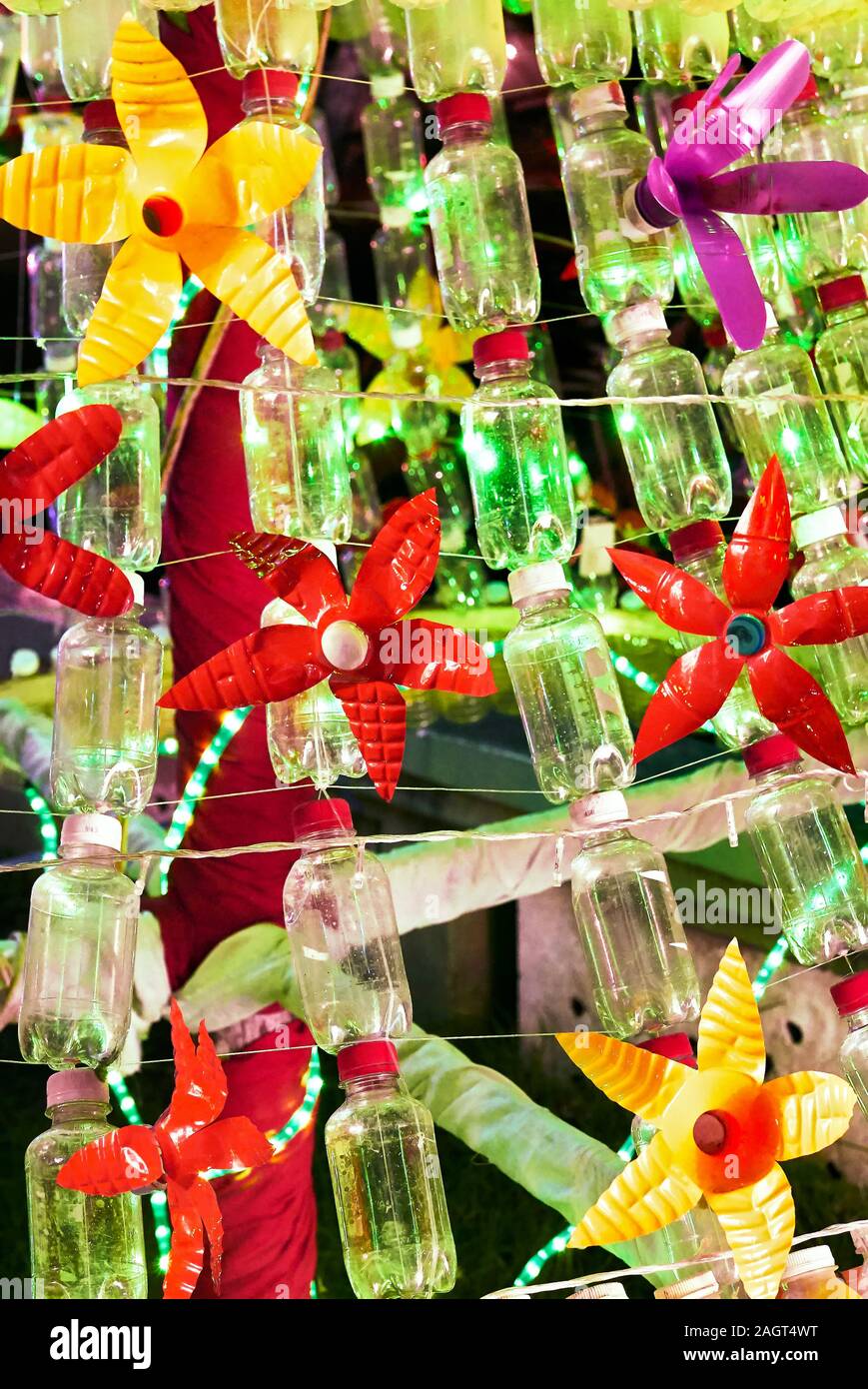 Nahaufnahme einer Weihnachtsdekoration aus recycelten Kunststoffen und leere Flaschen mit grünen Weihnachtsbeleuchtung im Hintergrund Stockfoto