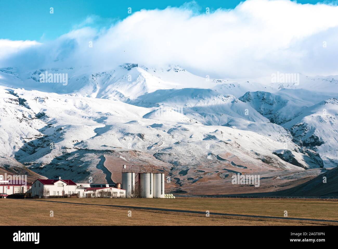 Nahaufnahme der schneebedeckten zerklüfteten Landschaft der Berge mit Kleine Häuser und Fabrik in einem Feld Stockfoto