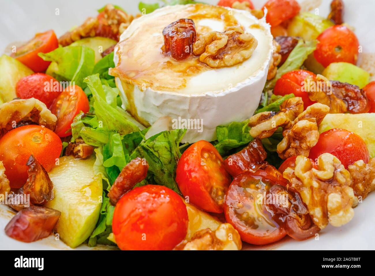 Gesundes Essen. Ziegenkäse Salat mit Tomaten, Äpfel, Nüsse und Termine Stockfoto