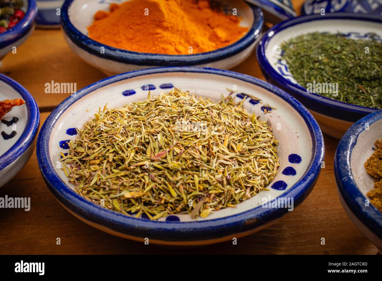 Gesundes Essen. Gewürze in Keramik Behälter typisch für Marokko auf einem alten Holztisch. Farbige Pfeffer, Kurkuma, Cayennepfeffer, Kreuzkümmel, Dill und Thymian Stockfoto