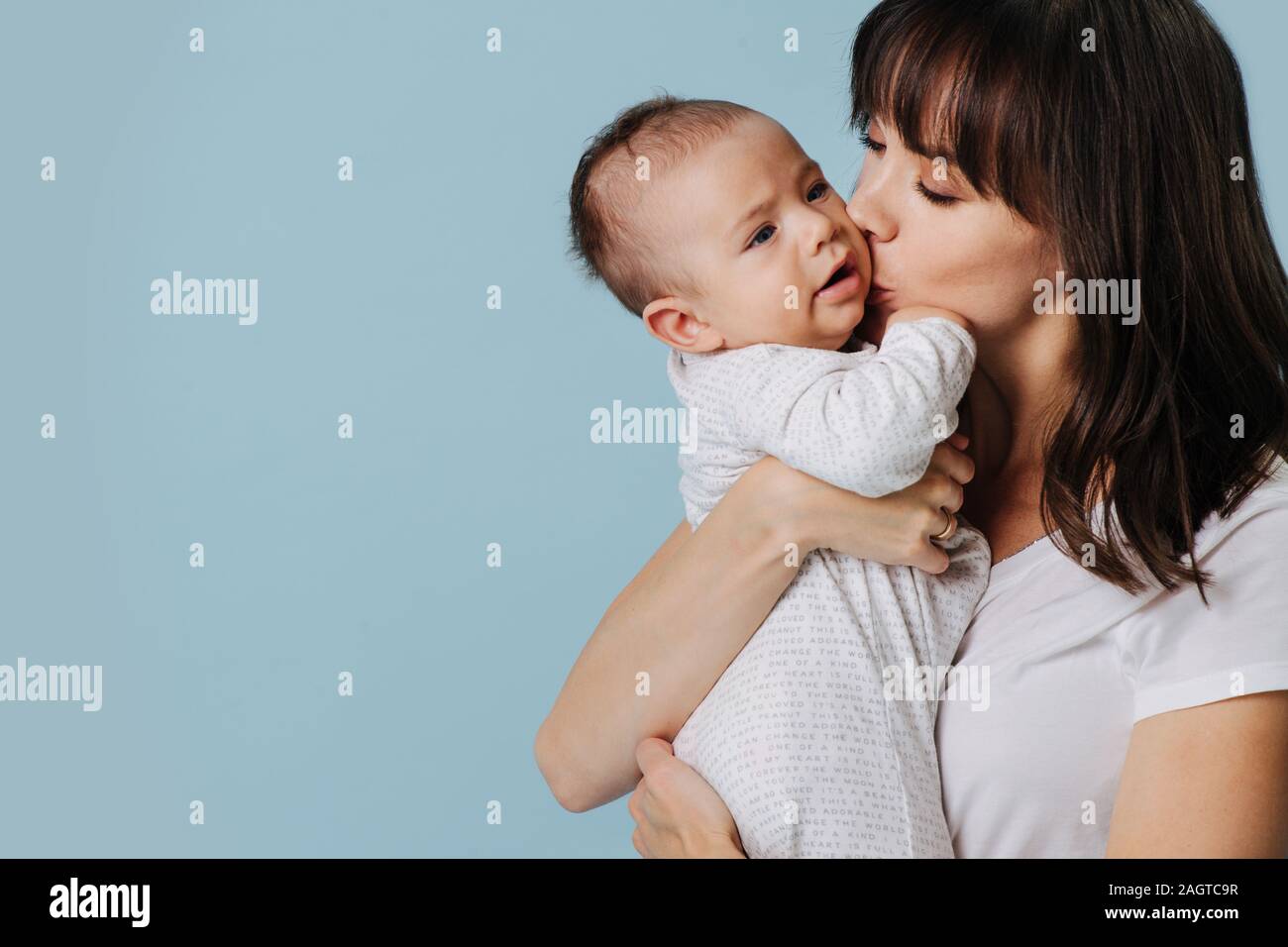 Liebevolle Mutter umarmt Baby und küssen, ihn in ihre Arme Stockfoto