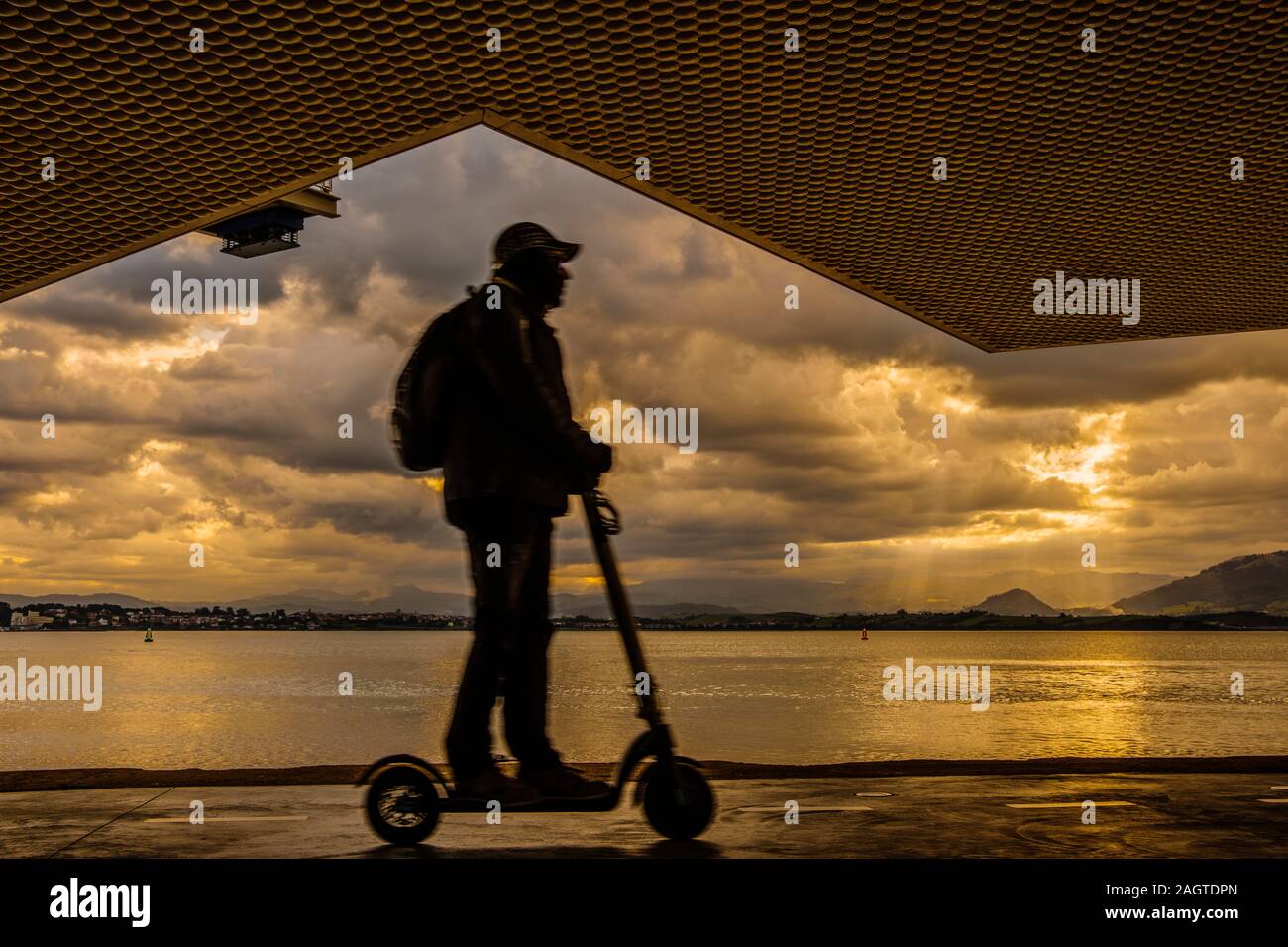 Person, die einen elektroroller bei Sonnenaufgang durch die Bucht bei Botin Center Museum Kunst und Kultur. Botin Stiftung, Architekten Renzo Piano. Santande Stockfoto