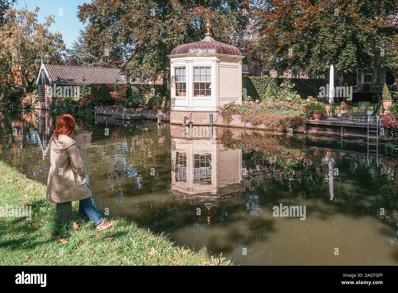 Edam, Niederlande, 22. September 2019: Frau genießt die Aussicht auf die Pavillons auf der Bank von den Kanal Nieuwe Oase in Edam in den Niederlanden Stockfoto