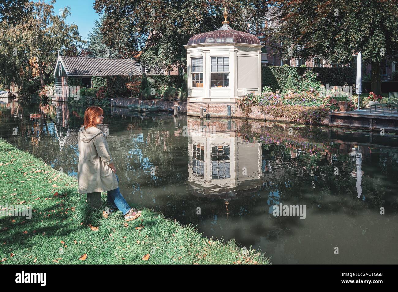 Edam, Niederlande, 22. September 2019: Frau genießt die Aussicht auf die Pavillons auf der Bank von den Kanal Nieuwe Oase in Edam in den Niederlanden Stockfoto