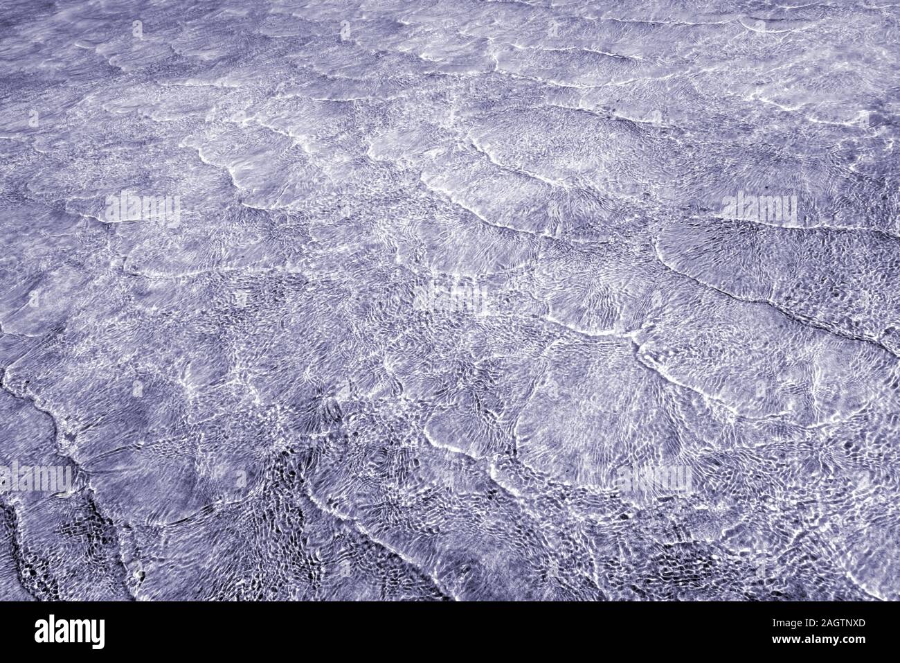 Leere abstrakt Hintergrund natürlich von kleinen Wellen des Meeres im flachen Wasser und Sonnenlicht Reflexionen auf Wasser Fläche erzeugt. Getönten in Mischung aus grauen Blu Stockfoto