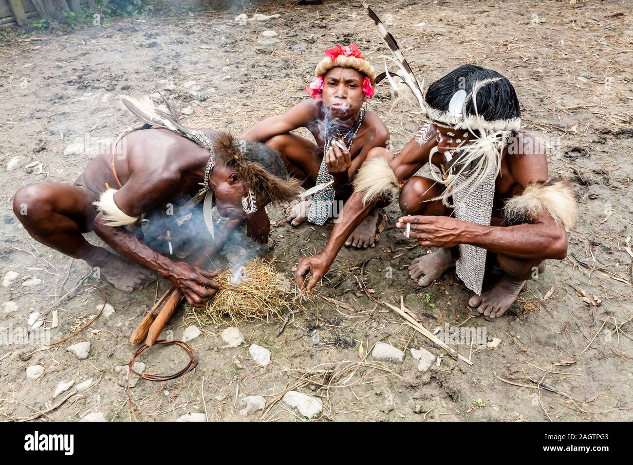 Wamena, Indonesien - Januar 9, 2010: Drei Männer der Dani Stamm in ein traditionelles Kleid das Rauchen einer Zigarette in Dugum Dani Dorf. Das Baliem Valley Papua Stockfoto
