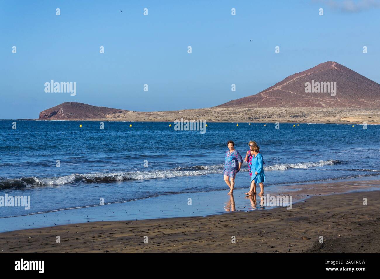 EL Medano, Spanien - 9. JULI 2019: älterer Frauen zu Fuß auf Playa El Medano Strand während sunrisee am 9. Juli 2019 in El Medano, Spanien. Stockfoto